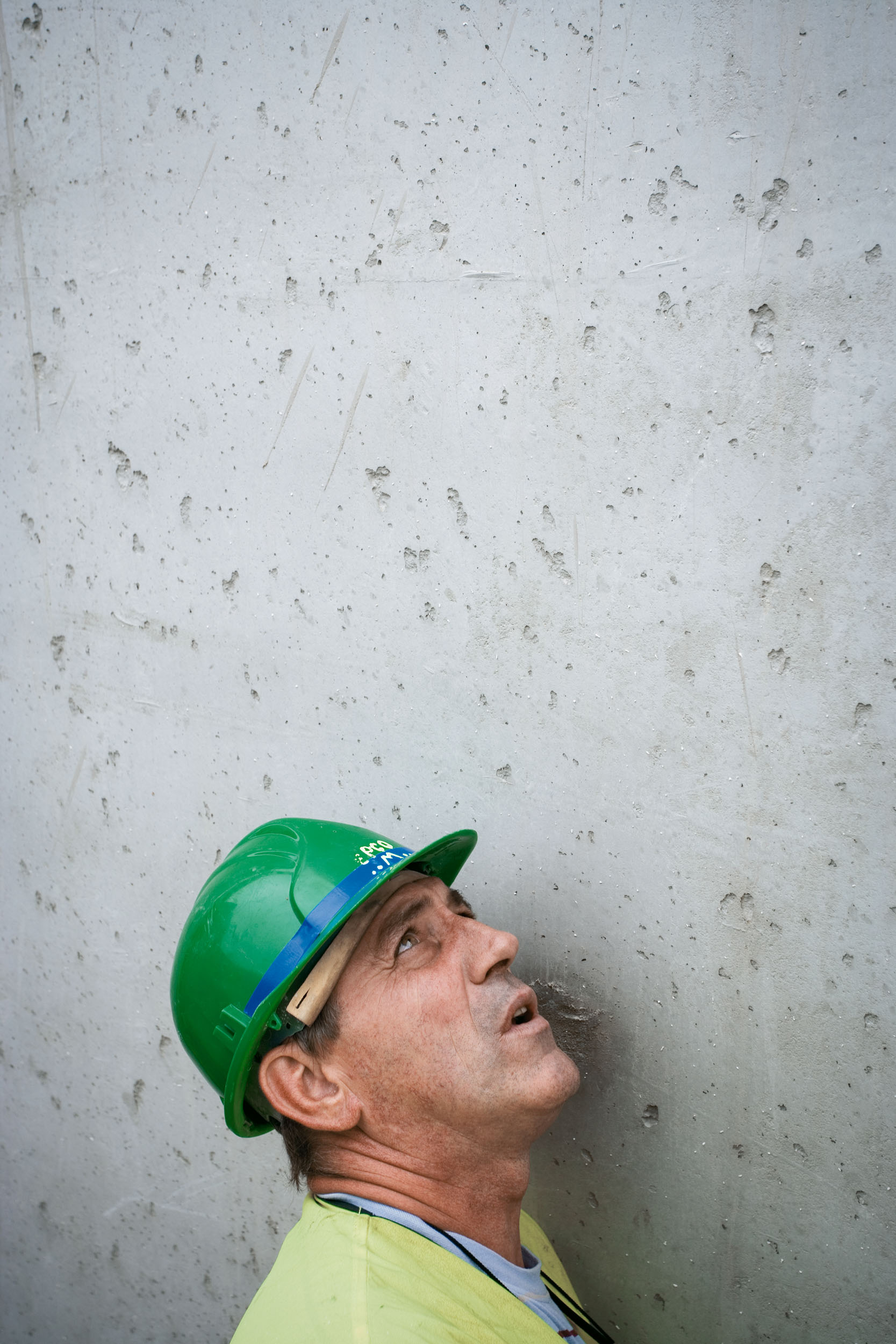 Portrait graphique d'un ouvrier casqué sur un fond de mur en béton fraîchement coulé. Un autre regard sur le reportage chantier BTP.
