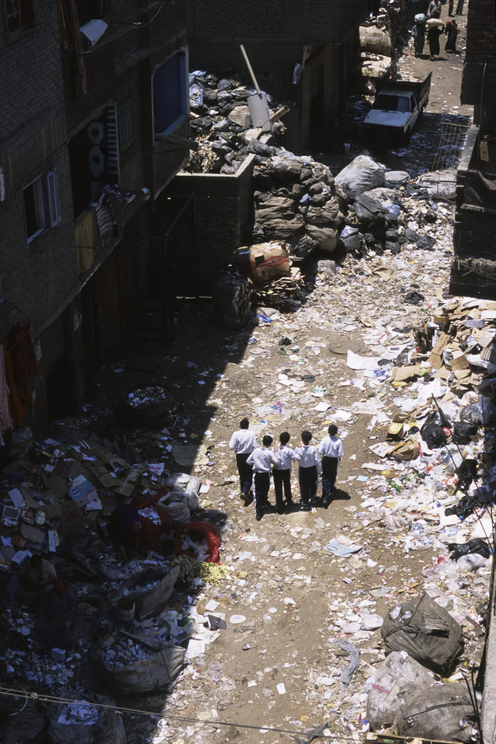 Écoliers sur le chemin de l'école au milieu des ordures dans une rue du quartier du Mokattam au Caire.