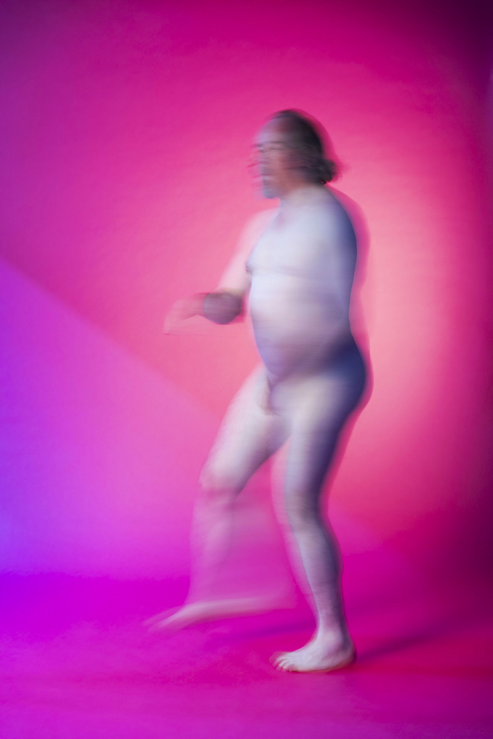 Portrait artistique d'un homme nu en mouvement sur fond rose. Photo de portrait de plain-pied réalisée en studio pour la banque d'images  Plainpicture.