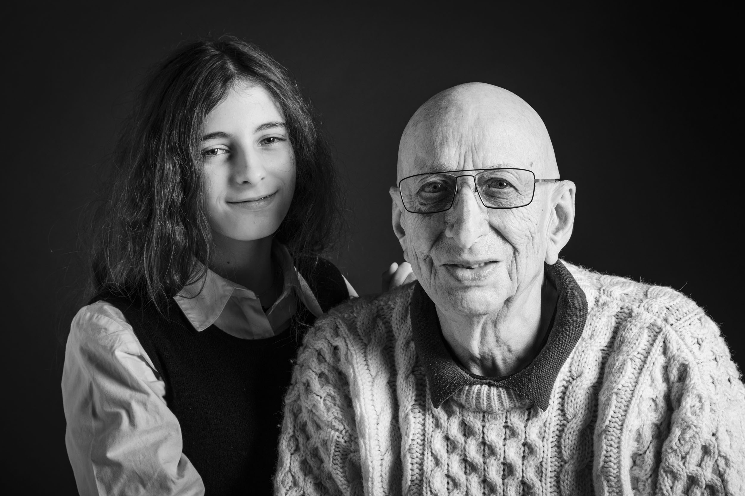 Portrait artistique en noir et blanc d'un grand père avec sa petite fille. Photo de portrait  réalisée en studio et cadrée en plan rapproché.