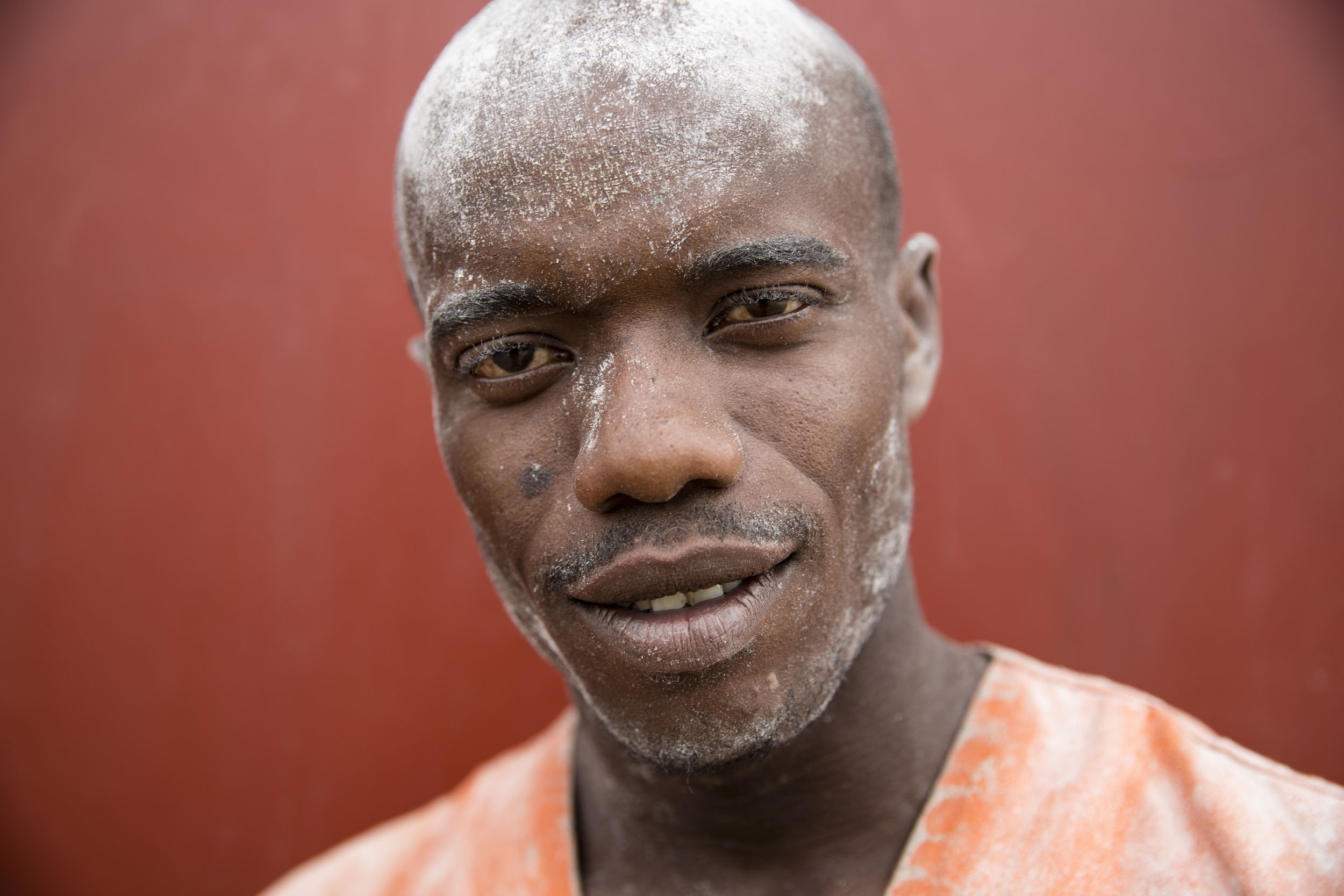 Portrait posé en gros plan d'un manutentionnaire sur le port industriel de Brazzaville au Congo. Il a de la farine sur le visage. Photo de portrait en reportage réalisé pour la société Nécotrans.