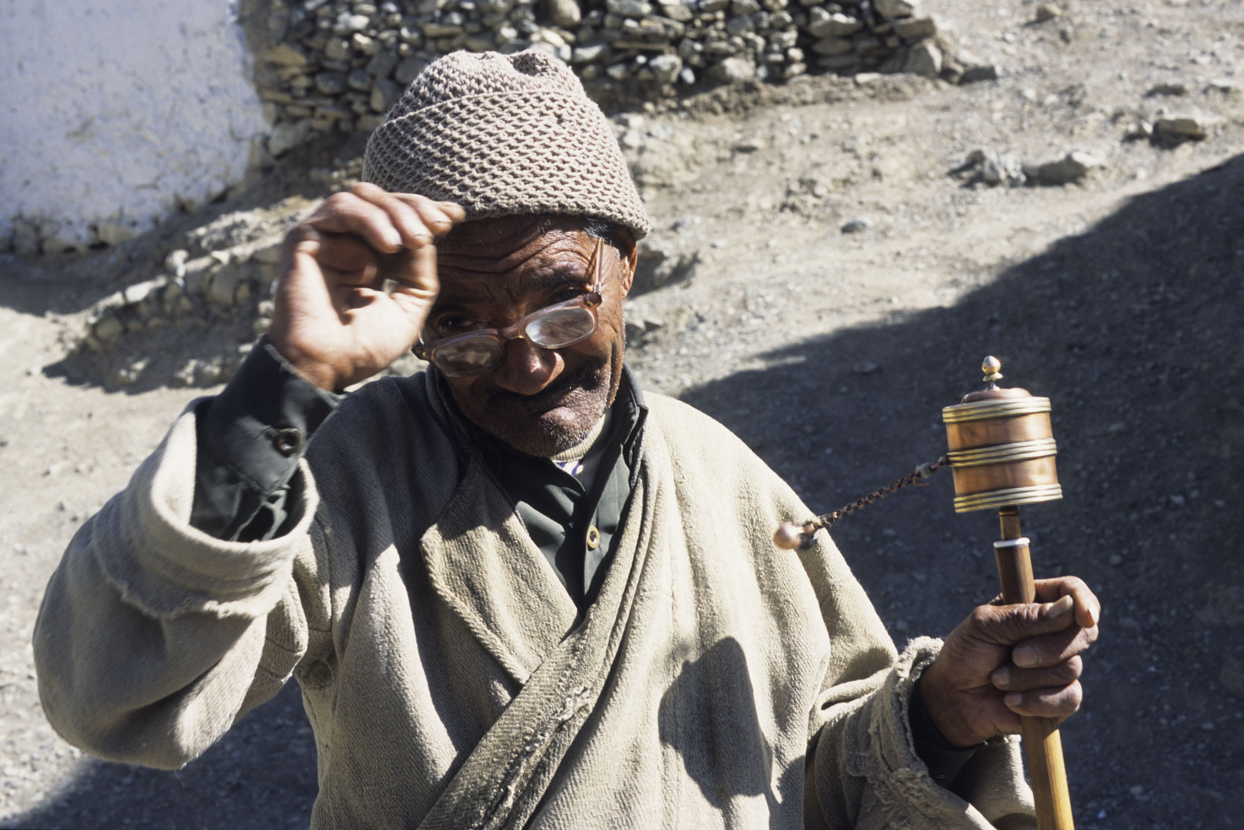 Portrait d'un vieil homme dans les rues de Lamayuru au Ladakh en Inde avec un moulin à prières dans la main. Photo de portrait en film inversible argentique.