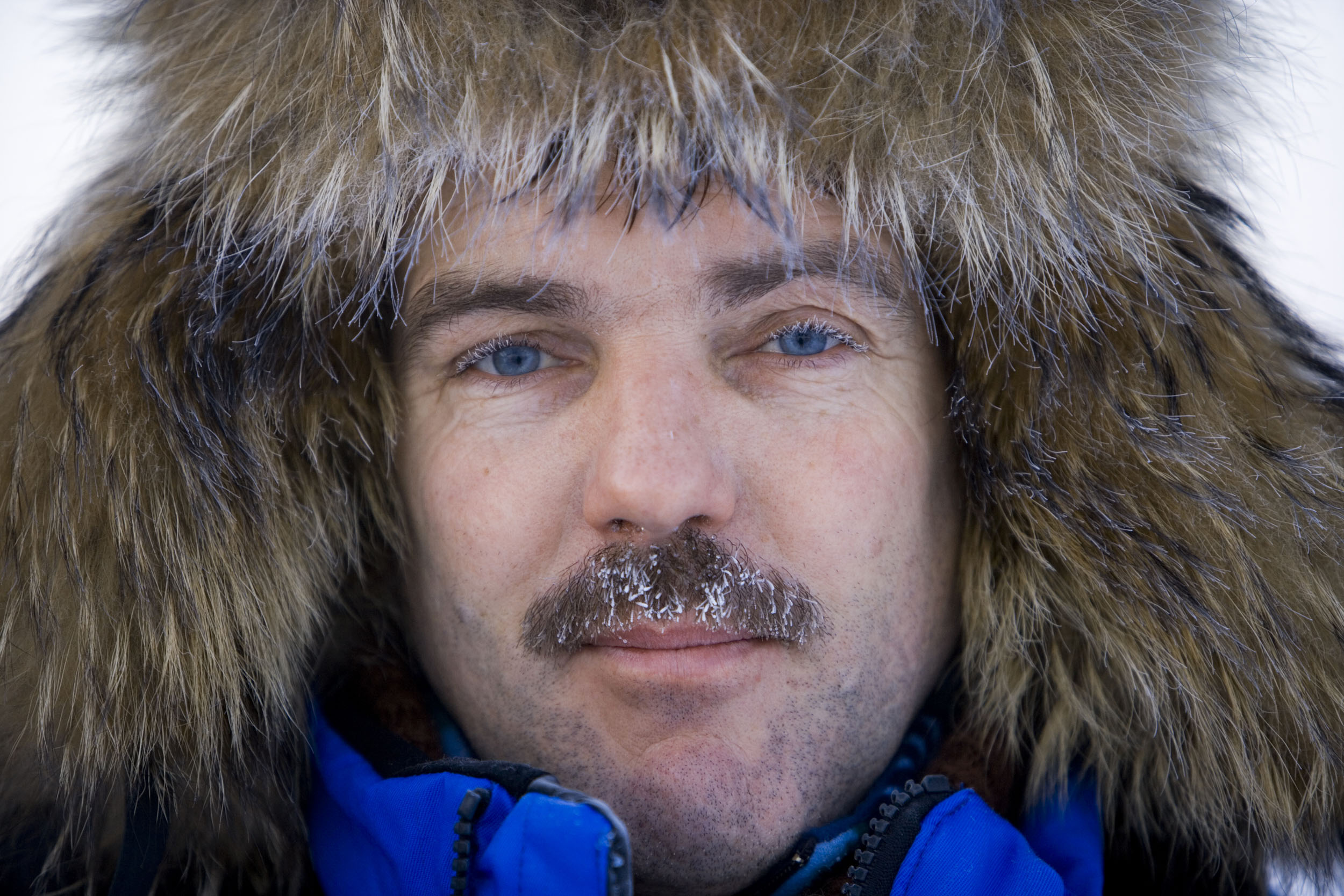 Portrait en gros plan d'un homme portant une chapka avec les moustaches givrés par le froid réalisé lors d'un reportage en Sibérie pour le Groupe Engie.