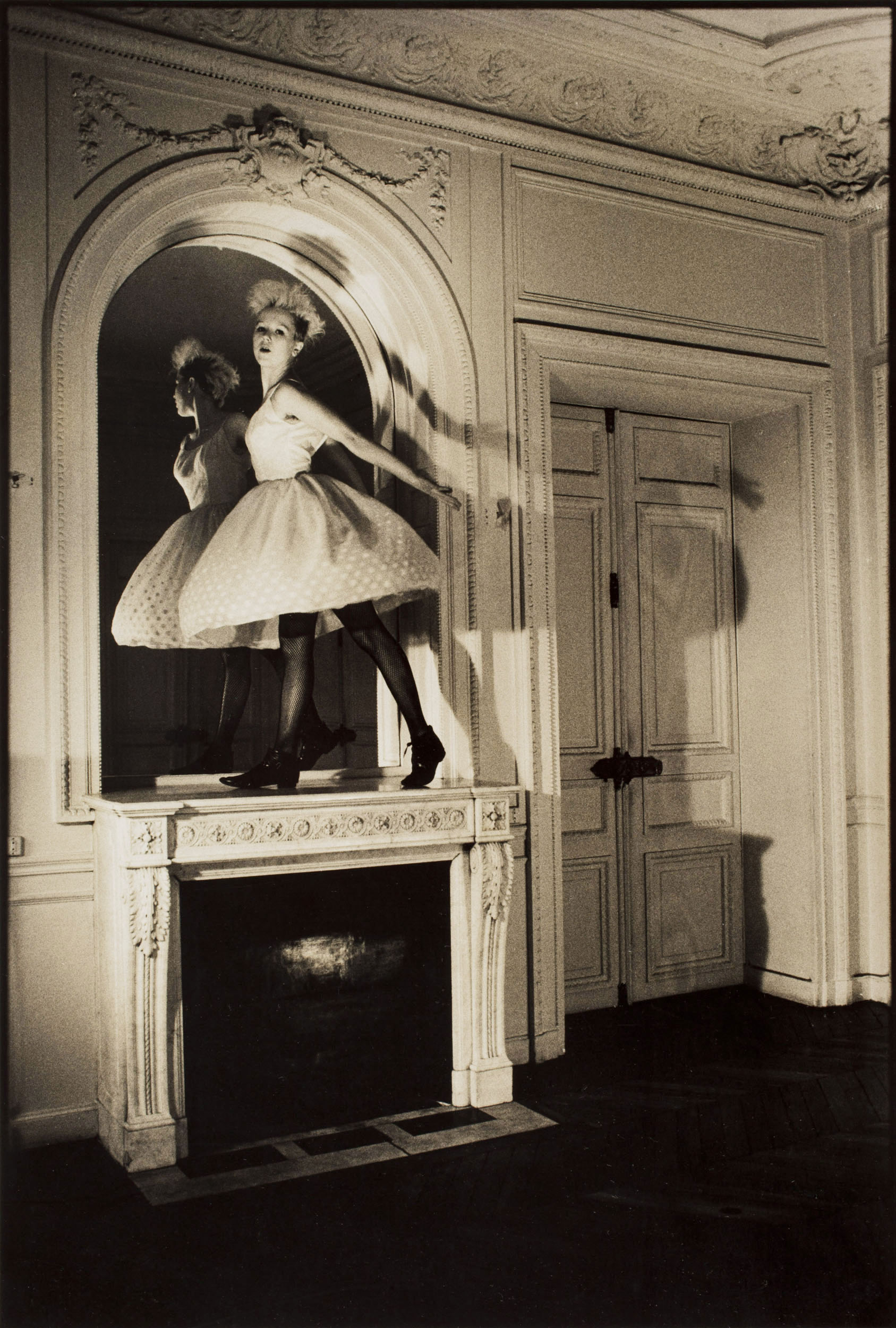 Portrait d'une danseuse debout en équilibre sur la cheminée d'un appartement haussmannien à Paris. Recherche personnelle - Argentique - 1984. Tirage vintage aux tons chauds. Lumière du jour et projecteurs Cremer.