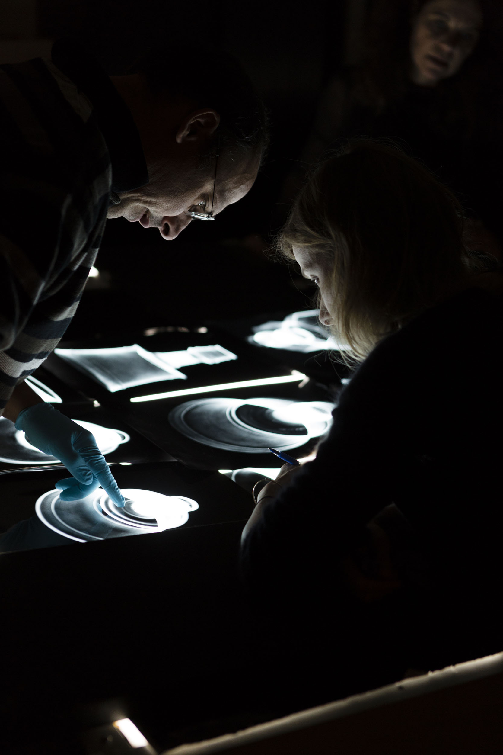 Un autre regard sur le reportage en entreprise.  Une femme et un homme analysent des radiographies d'objets d'art sur une table lumineuse. Reportage photographique commandé par le C2RMF, Centre de Recherche et de Restauration des Musées de France.