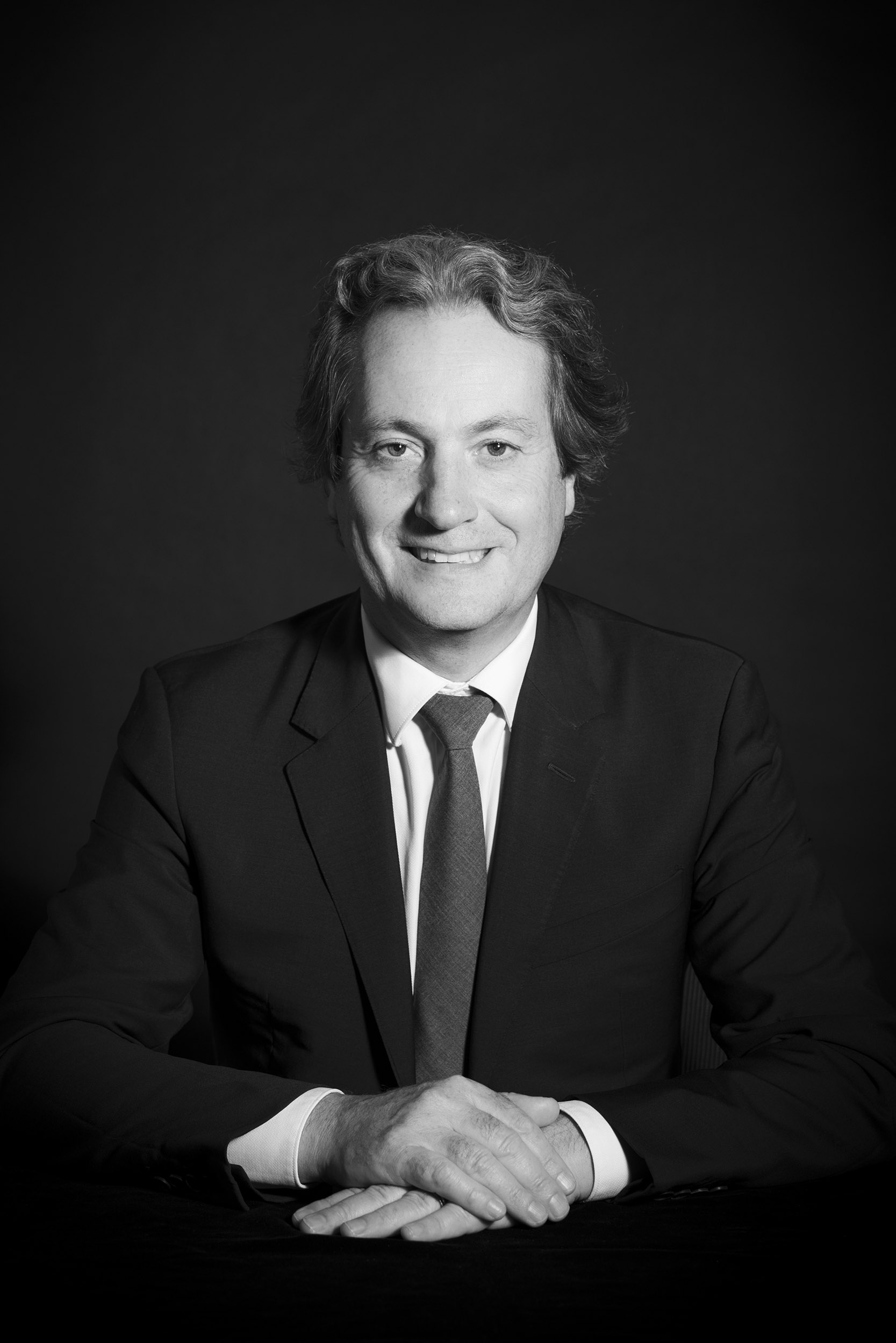 Photographie de portrait corporate en noir et blanc réalisée en studio à Paris d'un homme en costume cravate.